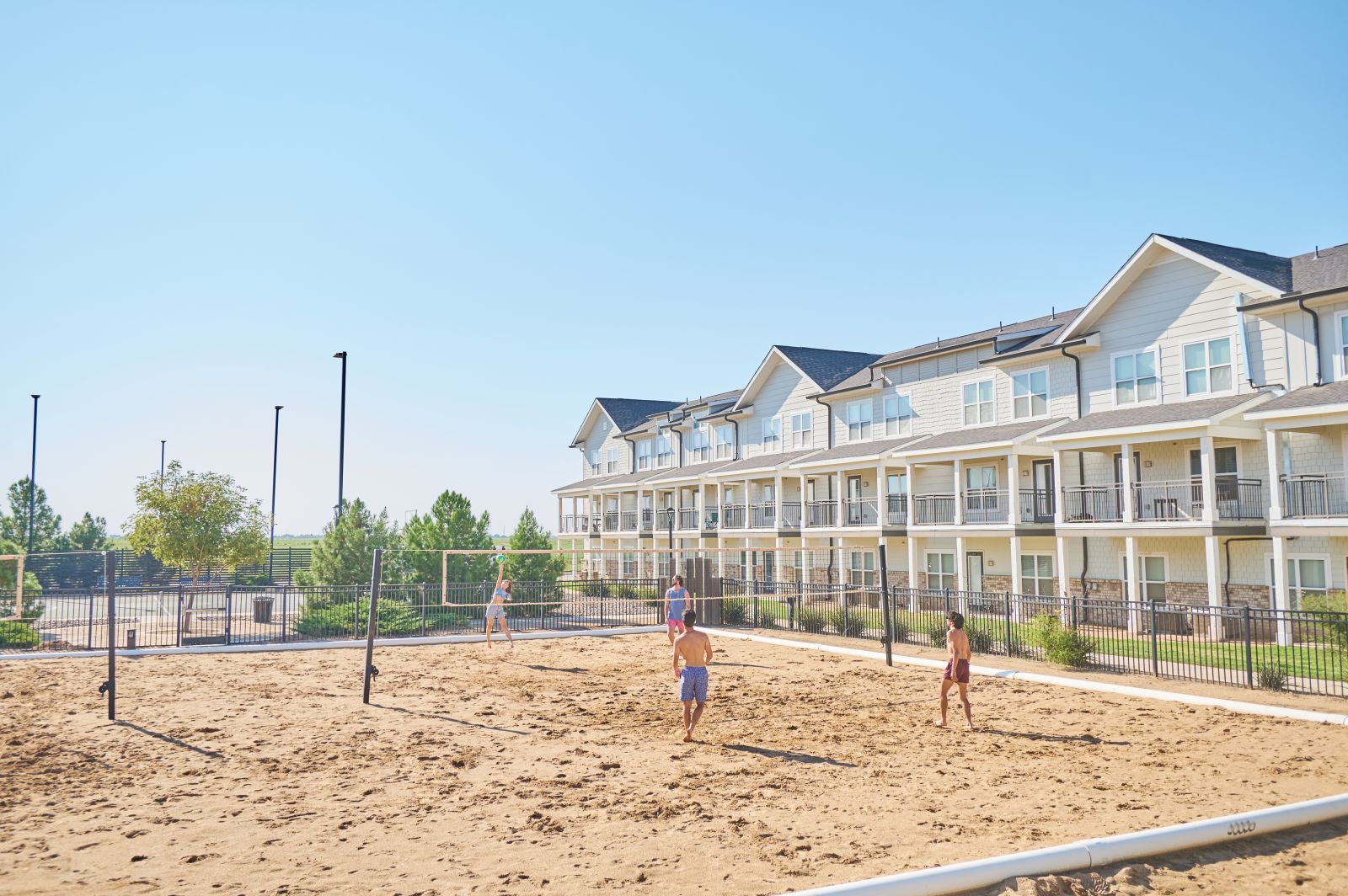 People playing sand volleyball outside apartment