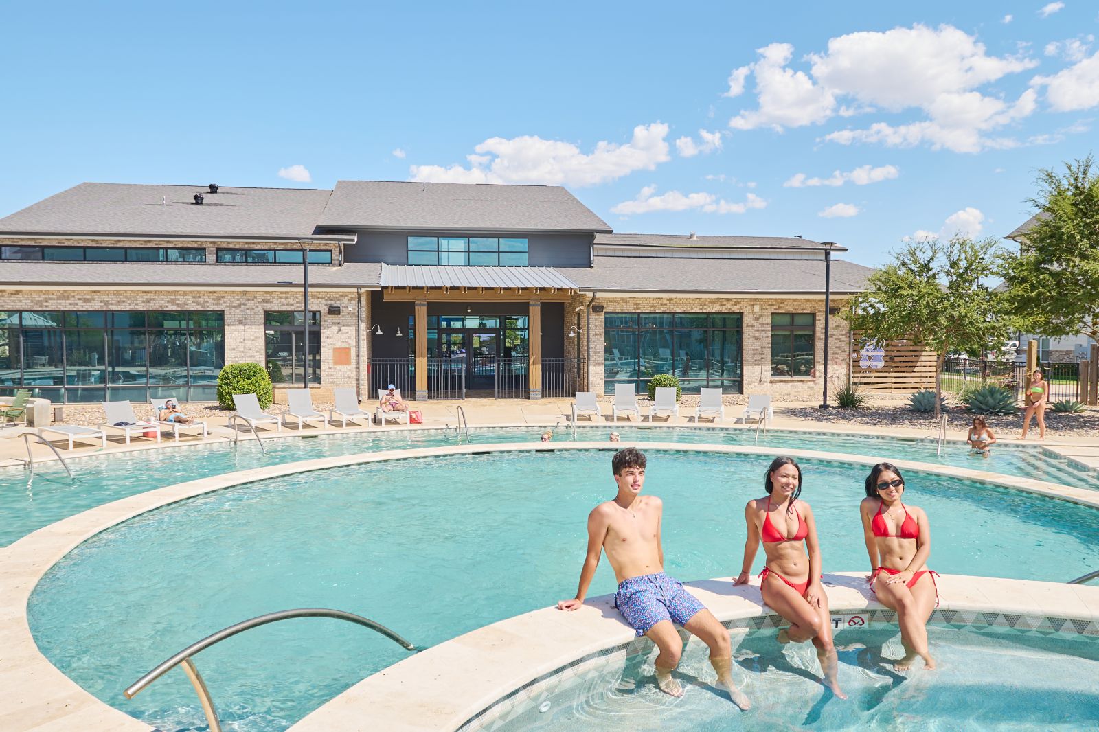 Three people sitting on ledge in pool