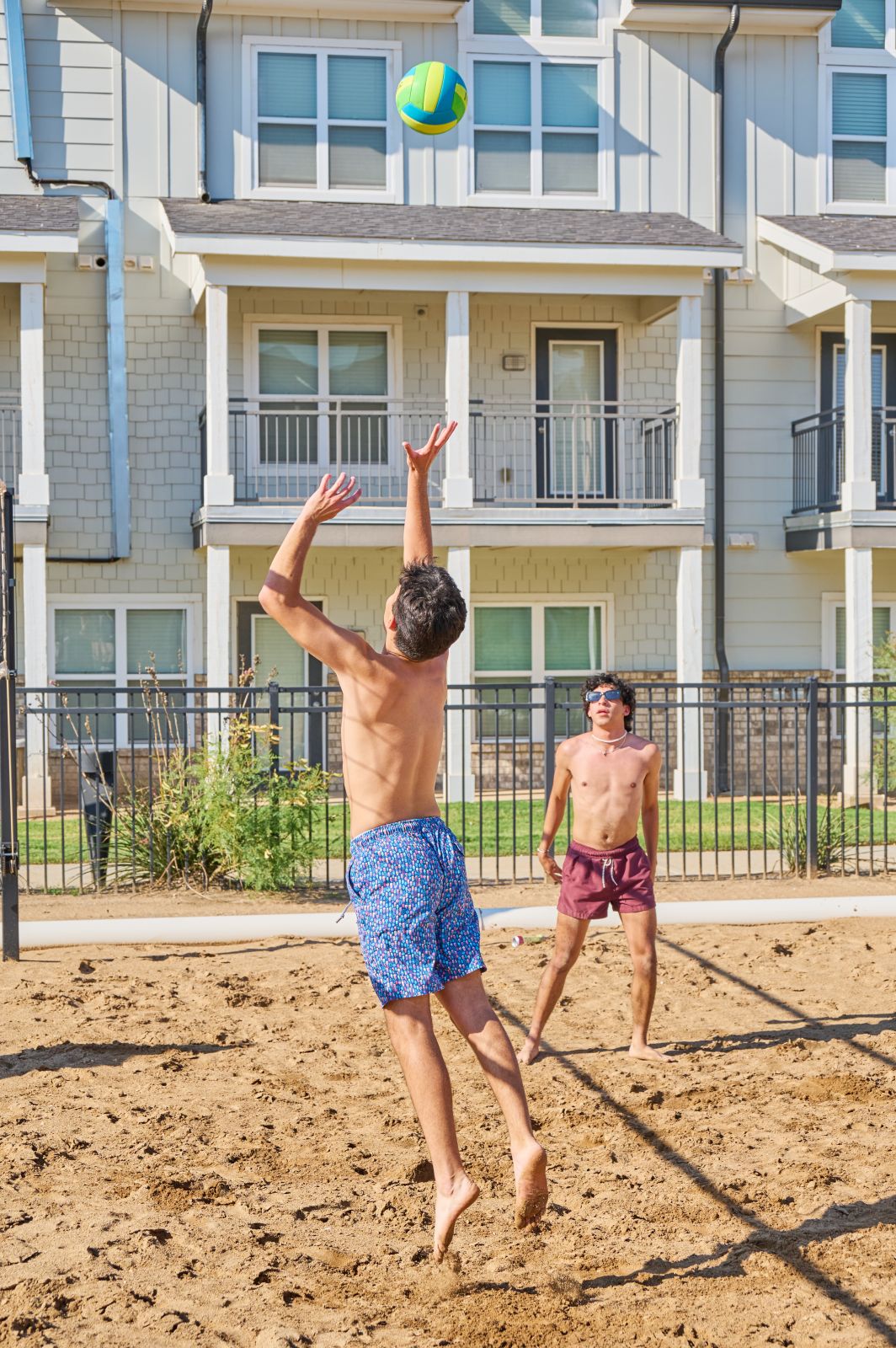 Boys play sand volleyball and serve the ball