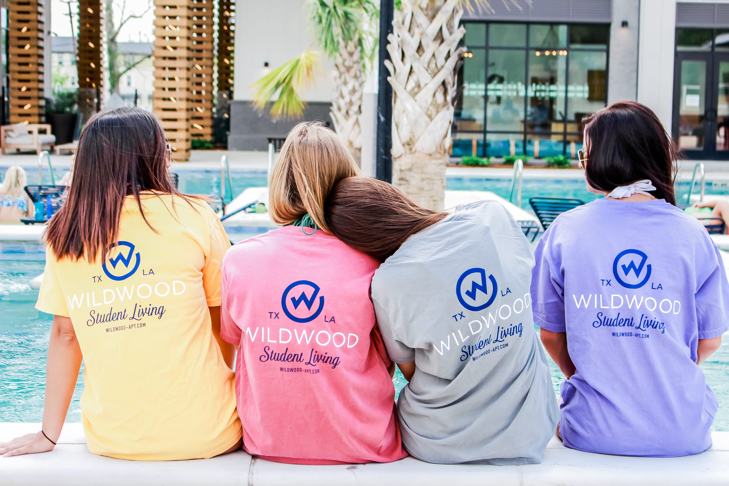 Four girls sitting in branded tshirts near a pool